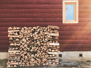 Stack of Maple Firewood in front of a log cabin